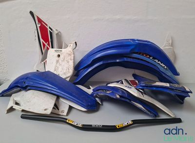 de nombreuses pièces de moto bleues et blanches posées sur une table
