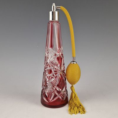 une bouteille en verre rouge avec un pompon jaune à côté