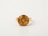 a close up of a ring with a brown stone on a white surface