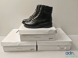 une paire de bottes noires posée sur une pile de cartons blancs