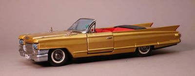une petite voiture en or avec un toit rouge sur fond gris