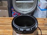 a black and silver electric pressure cooker on a wooden table