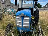 un tracteur bleu qui est garé dans l'herbe