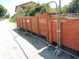 une grande benne orange derrière une clôture, au bord de la route
