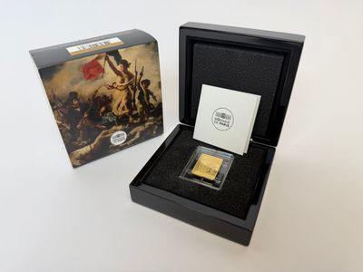 une pièce d'or dans une boîte noire posée à côté d'une boîte de cartes