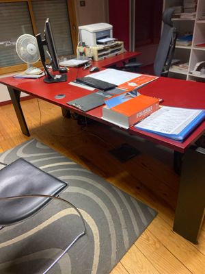 un bureau rouge avec une chaise noire dans un coin