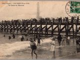 une vieille carte postale représentant des personnes debout sur un pont en bois au-dessus de l'eau
