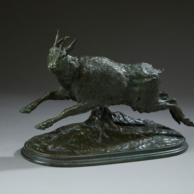 bronze sculpture of a running goat on a base on a gray surface