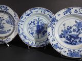 three blue and white plates with flowers and birds on them