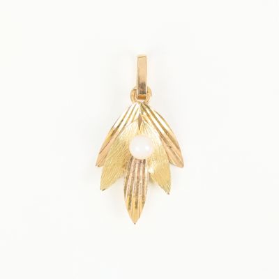 a close up of a gold pendant with a pearl in the center