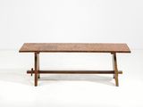 La table est en bois et son plateau est en osier tressé.