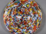 un bol multicolore posé sur une table, sur fond gris