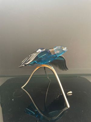 sculpture en verre représentant un oiseau posé sur un socle, sur une surface noire