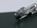 a small silver animal sitting on top of a green surface