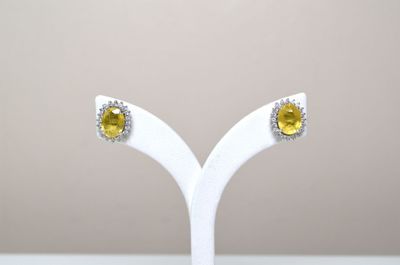paire de boucles d'oreilles à clous en saphir jaune et diamants, présentées sur un socle blanc
