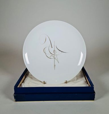 une assiette blanche ornée d'un dessin, dans une boîte bleue
