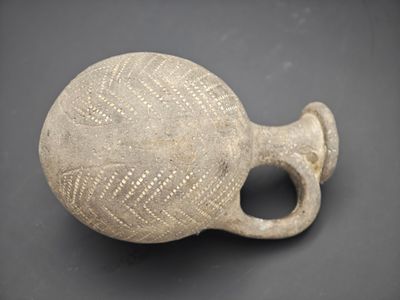 un petit vase muni d'une anse, posé sur une table