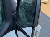 a side view mirror of a white truck on the side of the road