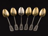 six silver and gold spoons on a black background