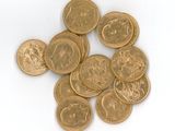 quelques pièces d'or posées sur une surface blanche, sur fond blanc