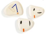 three ceramic plates with faces on them on a white surface