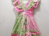 pink and green dress hanging on a hanger against a white wall