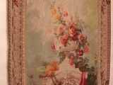 a tapestry hanging on the wall next to a vase of flowers
