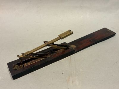 une vieille maquette de télescope en laiton et en bois posée sur une surface blanche