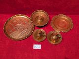 four antique brass candlesticks and a tray with a picture of a ship