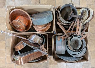 de nombreuses casseroles et poêles dans une boîte posée par terre