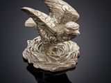une image représentant une statue en argent d'un oiseau perché sur un nid