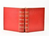 deux livres rouges sont ouverts sur une surface blanche