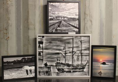 trois photos encadrées représentant un navire et un bateau, posées sur une table