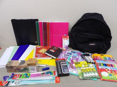 de nombreuses fournitures scolaires disposées par terre à côté d'un sac à dos