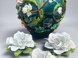 a green vase with white flowers on the side of it