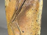 un vase marron orné d'un motif sur un fond gris