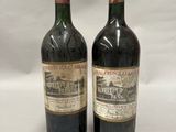 two bottles of wine sitting next to each other on a white surface