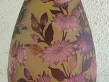 a yellow vase with pink flowers on it sitting on a table
