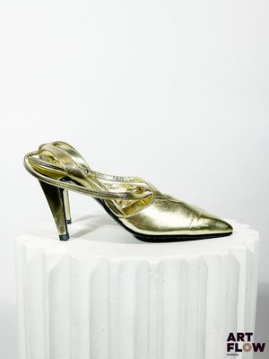 un gros plan sur une paire de chaussures dorées posées sur un socle blanc