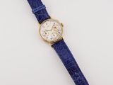 a close up of a watch on a white surface with a blue strap
