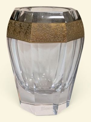 un vase en verre avec un couvercle doré, posé sur une surface blanche
