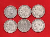 six types différents de pièces d'argent sur un fond rouge
