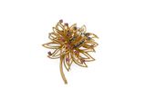 un gros plan sur une broche en or sertie de pierres roses et bleues