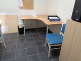 a desk with a computer and a chair in a small room
