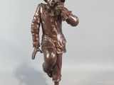 bronze statue of a man with a hat and a cane on a wooden base