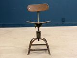 a wooden seat on a metal stool in front of a blue wall