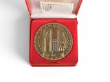 a gold medal sitting in a red box on a white surface