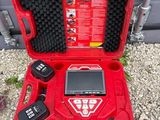 une mallette à outils rouge ouverte posée sur un sol recouvert de gravier