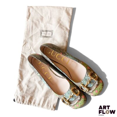 une paire de chaussures Gucci et un sac posés sur une surface blanche