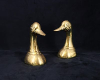 une paire de serre-livres en laiton en forme de tête de canard sur fond noir